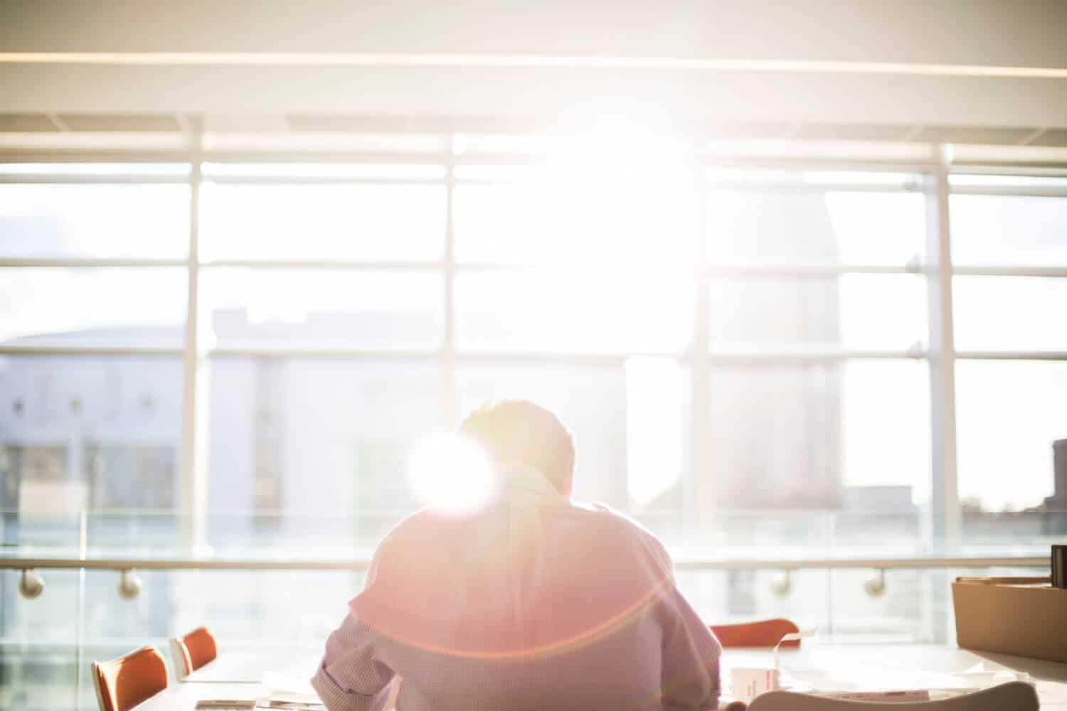 person at desk with sun shining in