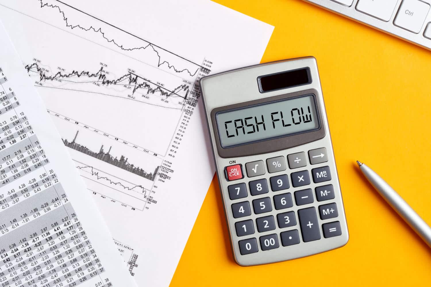 The word cash flow displays on a calculator screen with a business office desktop.